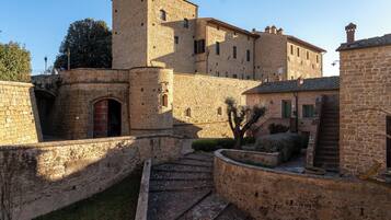 A historic stone building with a tower, arched entrance, and a staircase leading to a courtyard.