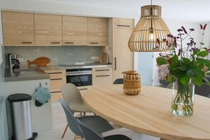 Una cocina moderna con armarios de madera, una mesa redonda para comer y una lámpara colgante.