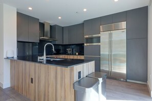 A modern kitchen with a central island, stainless steel appliances, and wooden cabinetry. - Walkable & Sleek LA Condo w/ Private Office (Los Angeles)