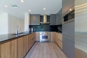 Eine moderne Küche mit Einbauofen, Edelstahlgeräten und Holzkorpussen.