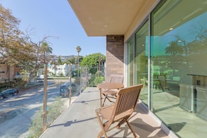 Ein Balkon mit Tisch und Stühlen, mit Blick auf eine Straße mit Autos und Gebäuden.