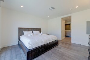 Ein modernes Schlafzimmer mit einem großen Bett, einem Holz-Kopfteil und einem begehbaren Kleiderschrank.