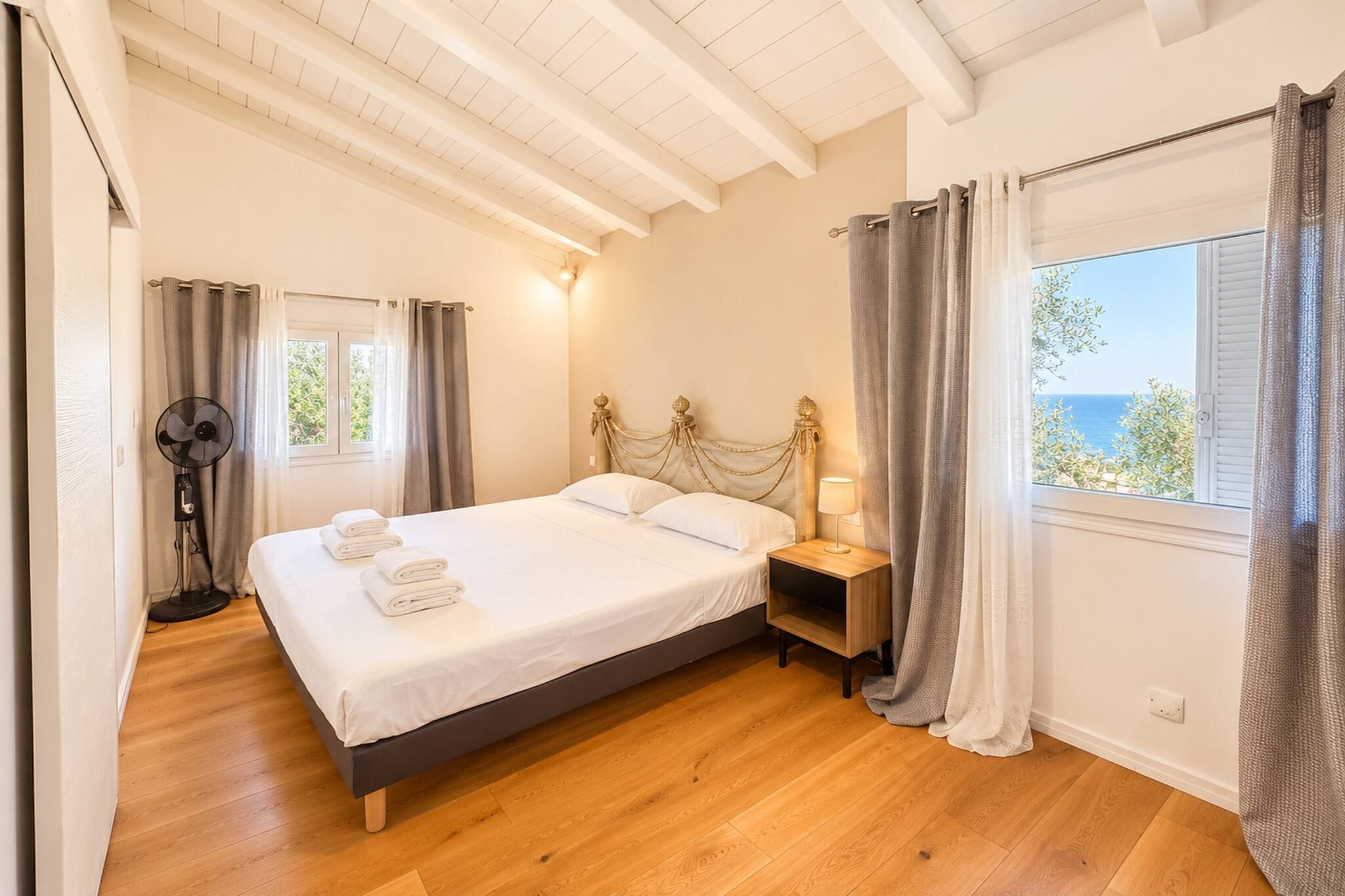 Een slaapkamer met een bed, nachtkastje, lamp en gordijnen.