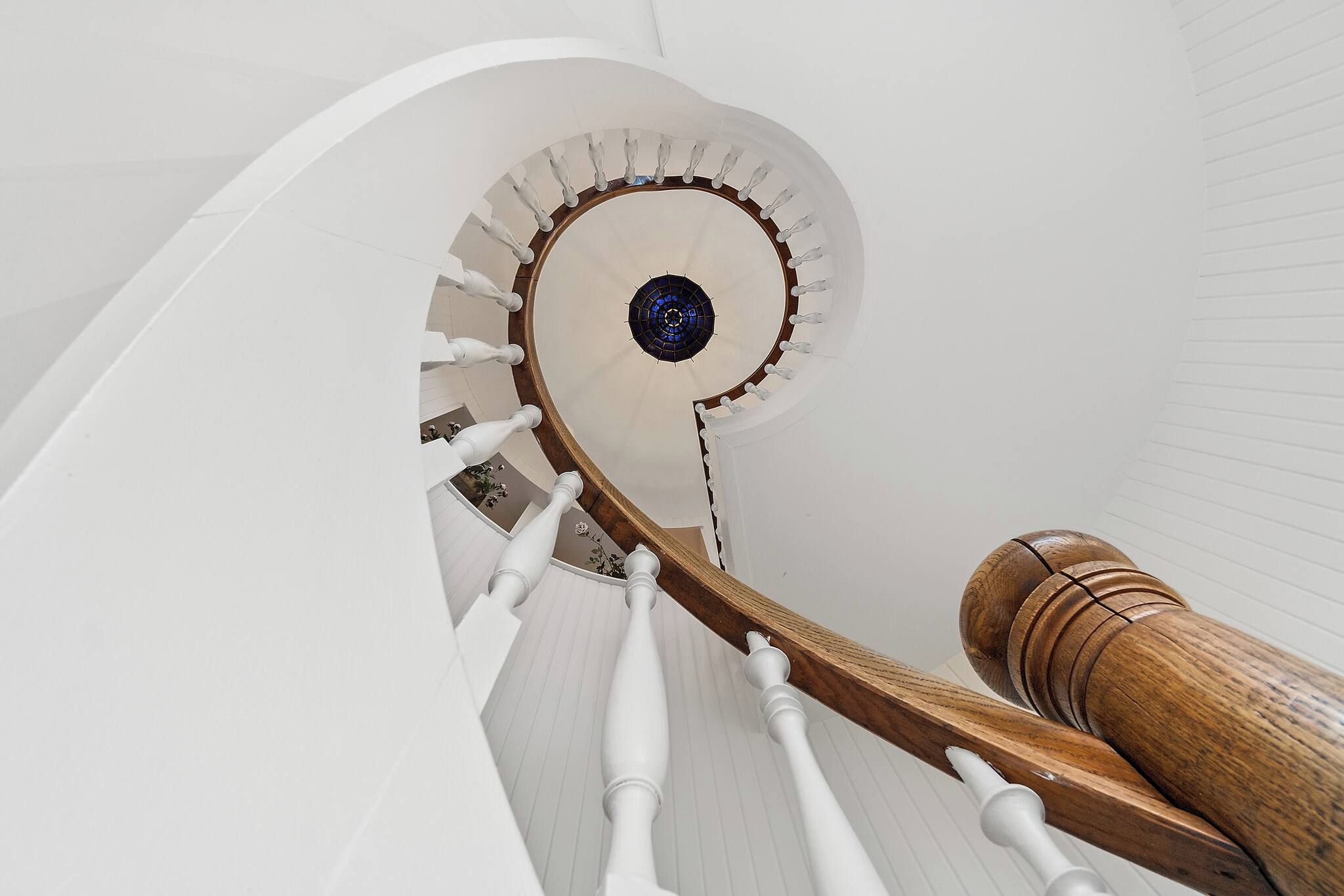 En spiraltrappe med hvide gelændere og et træværkshåndgreb.