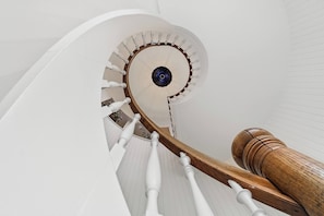 Una escalera en espiral con balaustres blancos y barandilla de madera.