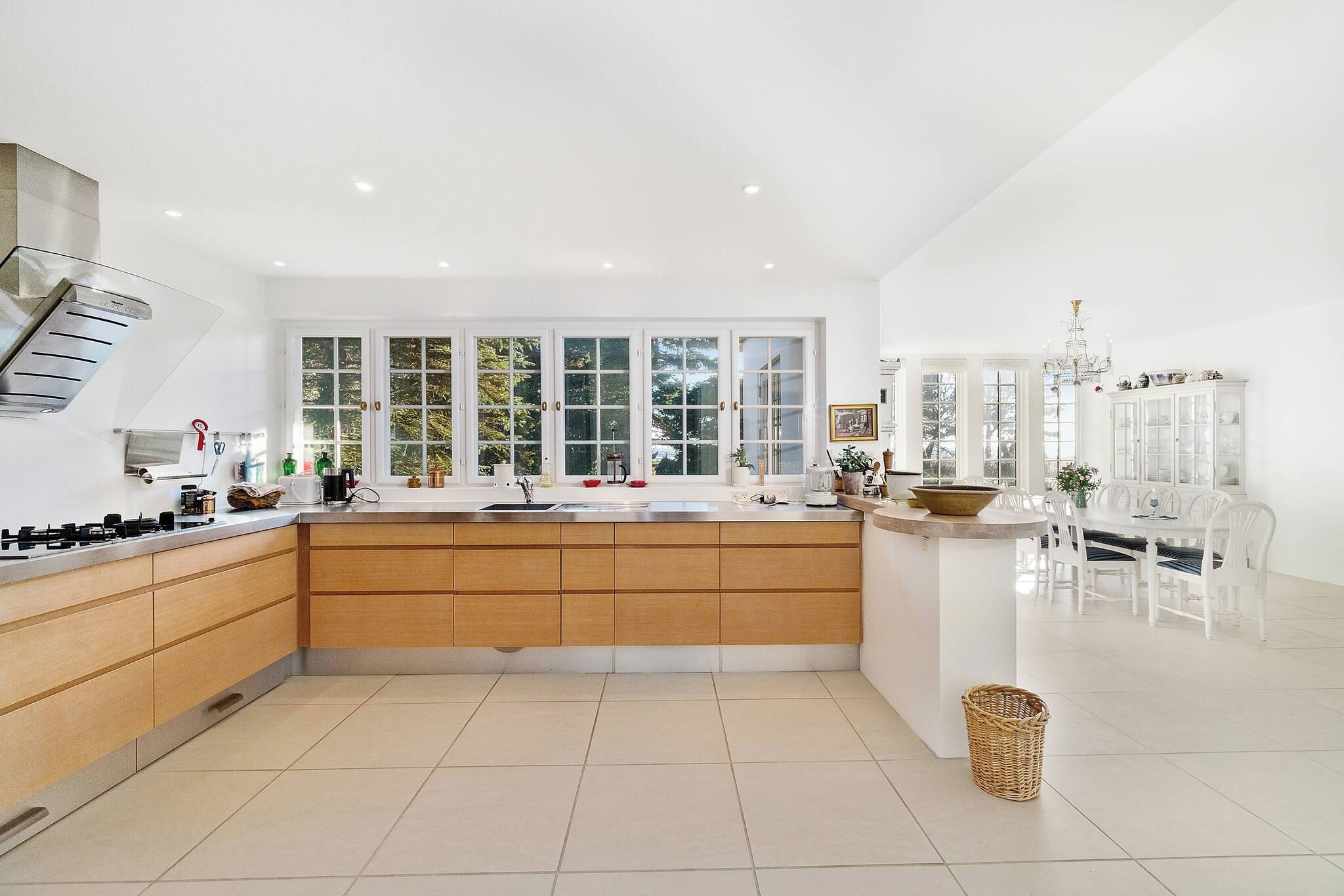 A modern kitchen with a central island, white cabinetry, and large windows.
