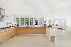 A modern kitchen with a central island, white cabinetry, and large windows.