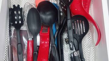 Un cajón con varios utensilios de cocina, incluyendo una espátula roja, una espátula negra y una espátula azul.