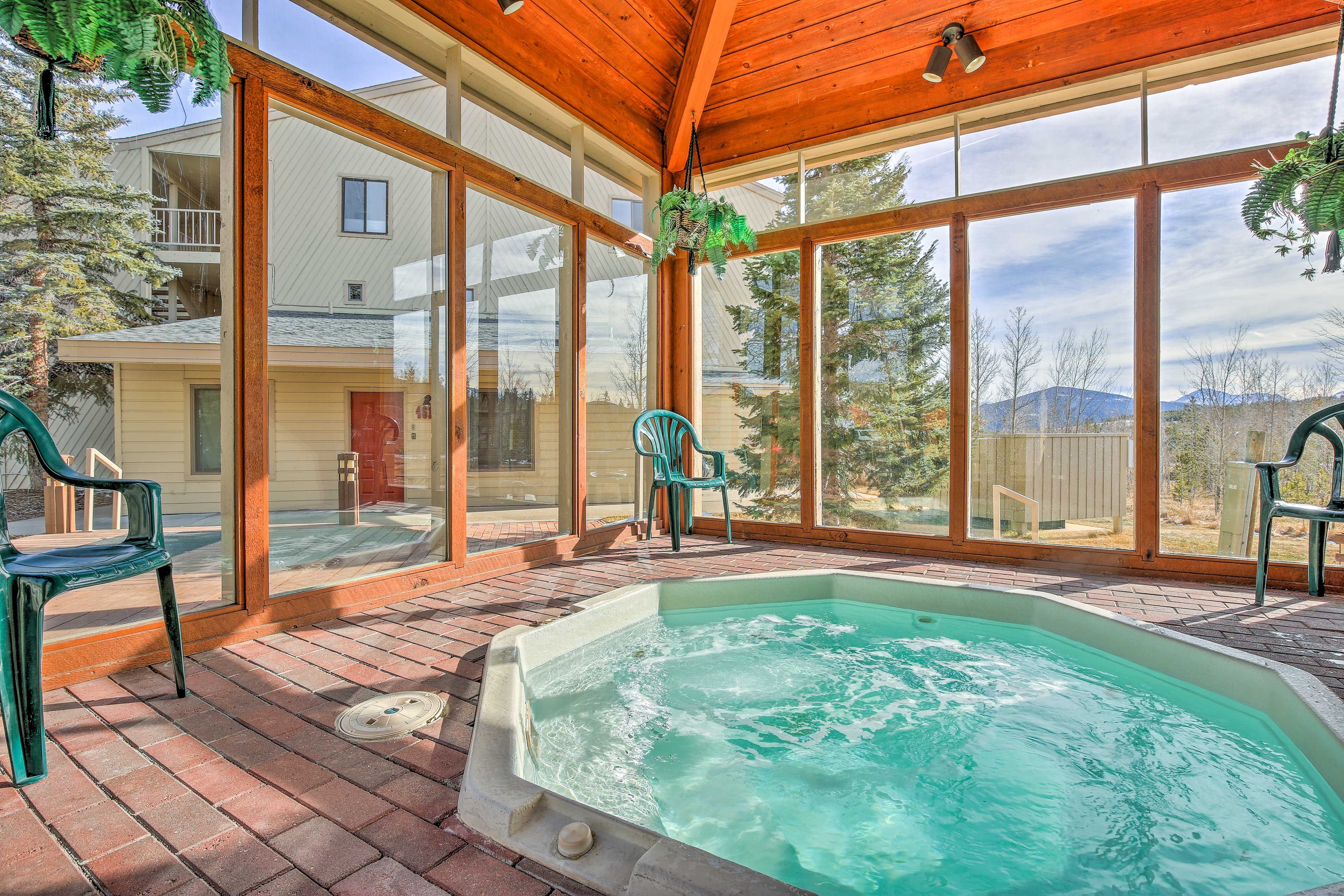 Un espace extérieur abrité comprenant un jacuzzi, un sol en briques et de grandes fenêtres donnant sur un quartier résidentiel.