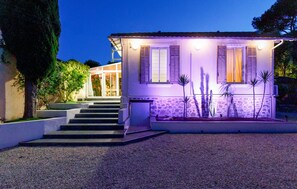 Ein zweigeschossiges Haus mit einer Steinfassade, einer Treppe zum Eingang und einem kleinen Garten mit Kakteen.