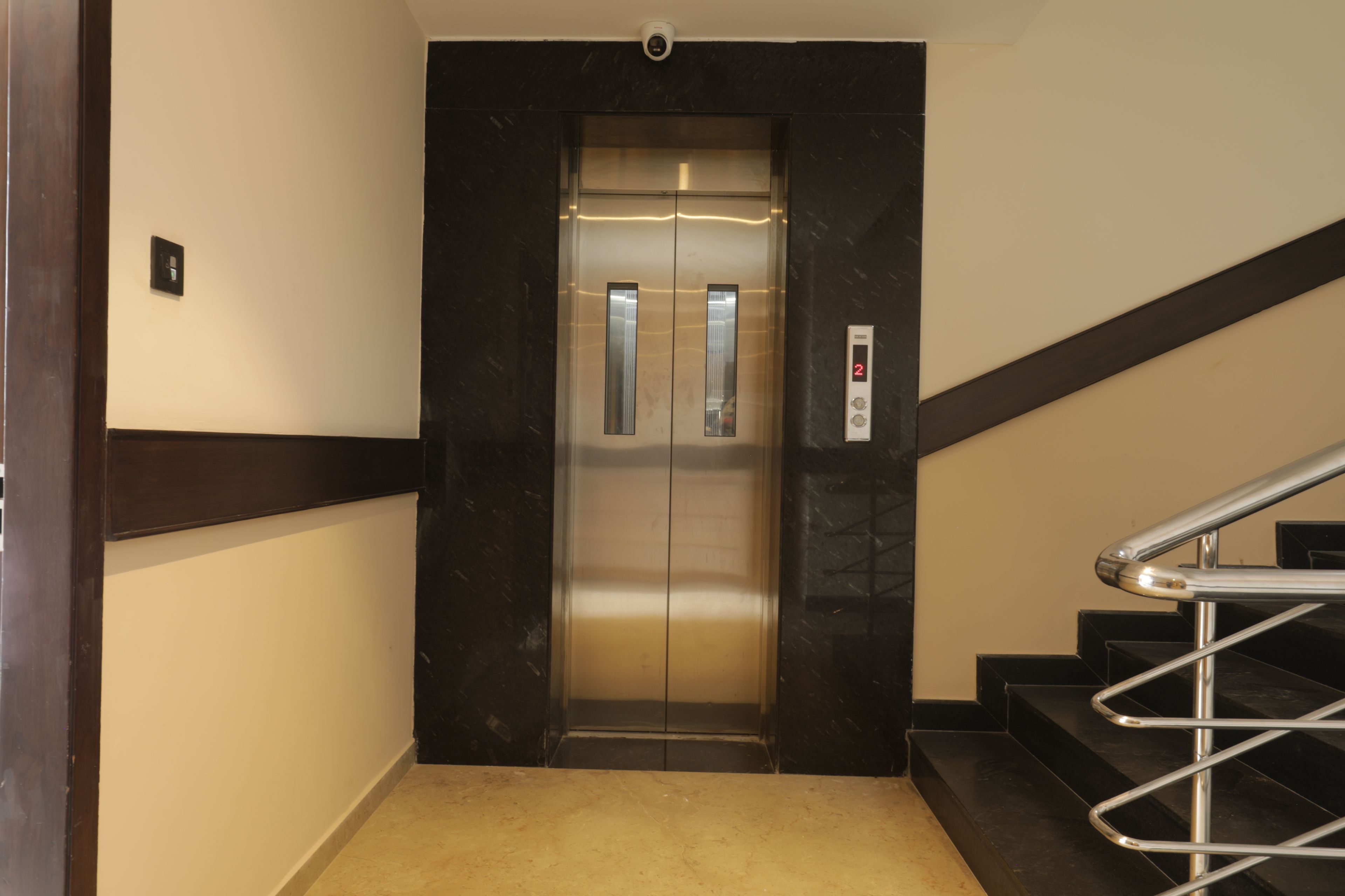 An elevator with a digital display, a handrail, and a carpeted floor.