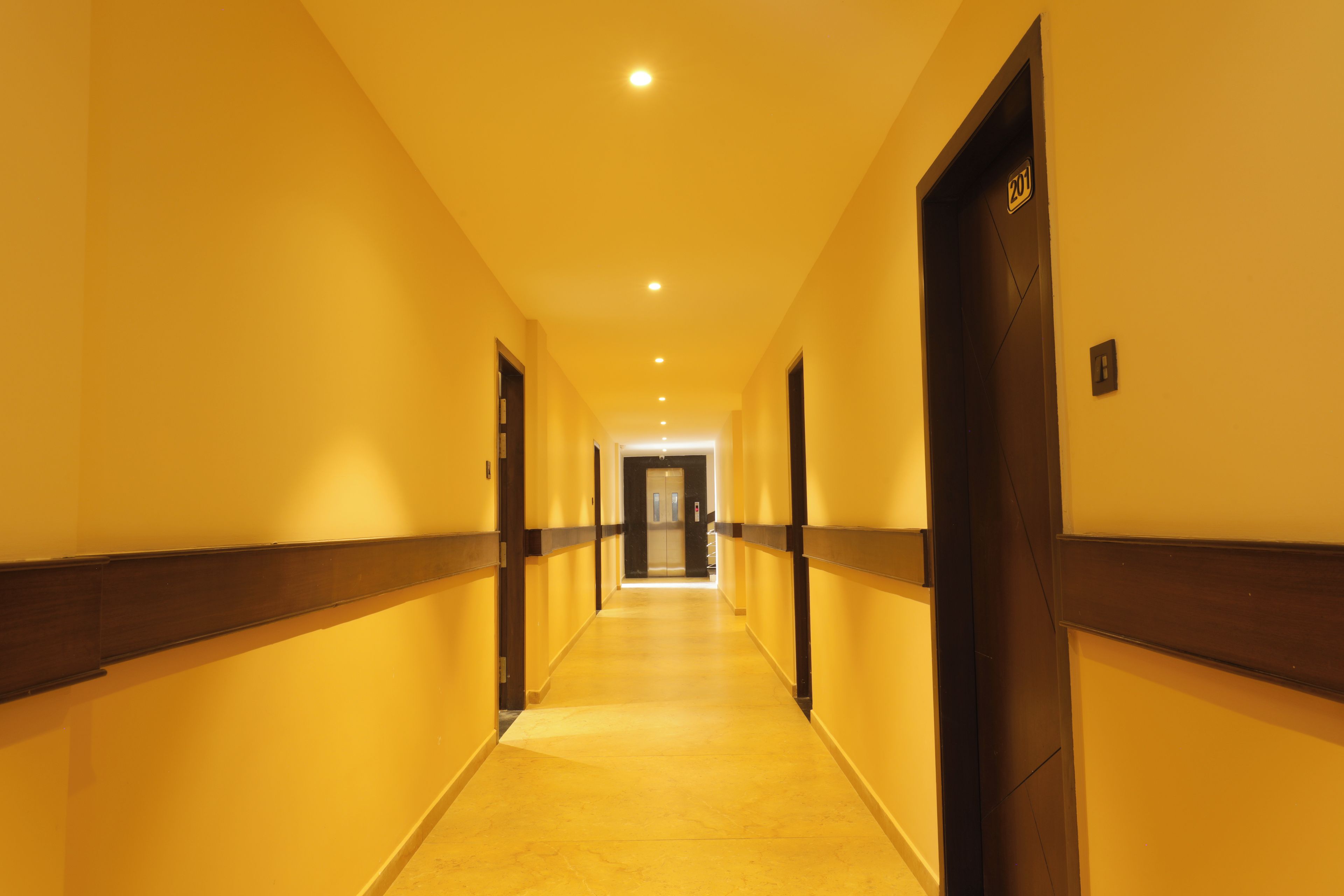 Un couloir d’hôtel avec des portes des deux côtés, un sol carrelé et un plafond doté d’un éclairage encastré.