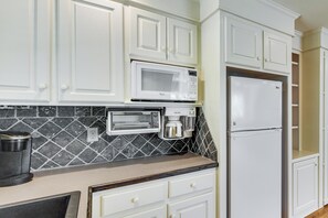 A kitchen with white cabinets, a microwave, a toaster oven, a coffee maker, and a refrigerator. - Dock, Hot Tub, Game Room! Lake Wateree Retreat (Camden)