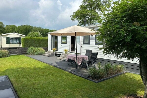 A mobile home with a patio area featuring a table and chairs under a canopy.
