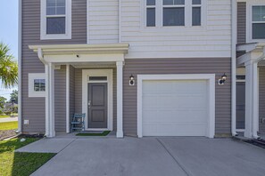 A two-story house with a front porch, a garage door, and a small entryway with a door. - NMB Golf Retreat Near NMB Sports Complex (Little River)