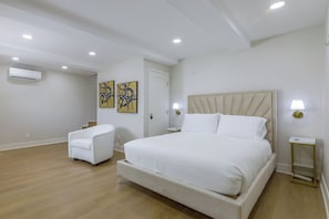 Een hotelkamer met een bed, een stoel, een nachtkastje en een wandairconditioner.
