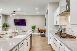 Cocina moderna con una isla central, muebles blancos y un comedor con mesa y sillas.