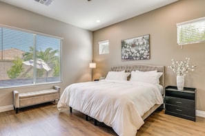 A bedroom with a large bed, a nightstand, a lamp, and a window with blinds. - Gather - Relax - Stay Awhile - Near Ballparks Mts (Goodyear)