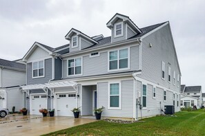 Ein zweistöckiges Wohnhaus mit Garage, überdachter Veranda und gepflegtem Rasen.