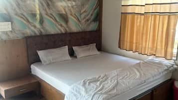 A bedroom with a wooden bed, a headboard with a marble-like design, and a herringbone-patterned floor.