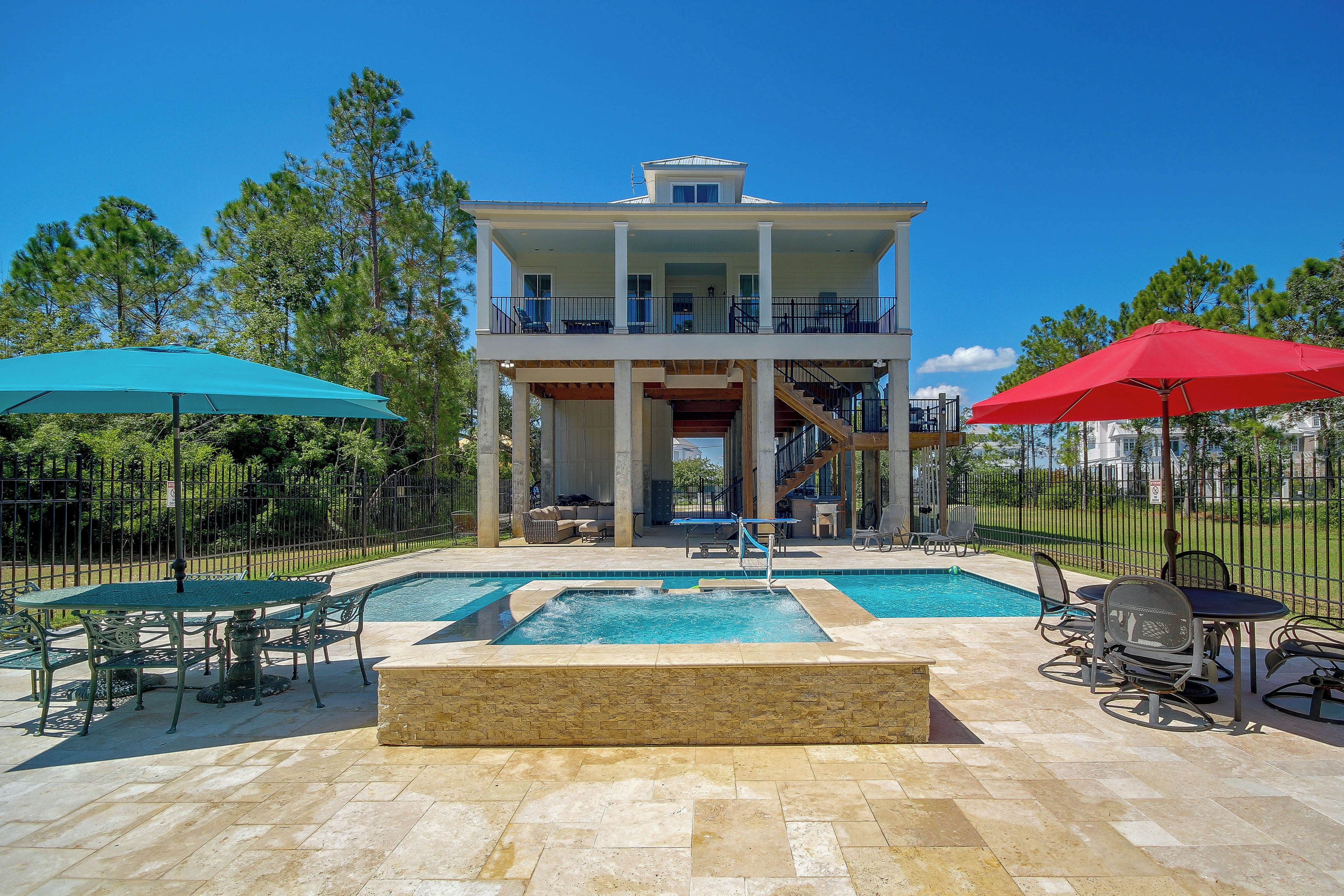A two-story building with a balcony, a swimming pool, and outdoor seating.
