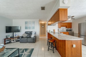 A modern kitchen with wooden cabinets, a stainless steel refrigerator, and a built-in microwave. - Beach Days + Chartered Boat Tours! PCB Retreat (Panama City Beach)