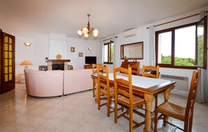 A dining area with a wooden table and chairs, a sofa, a fireplace, and a television. - HAUT DE VILLA VUE MER AU CALME (CERVIONE)