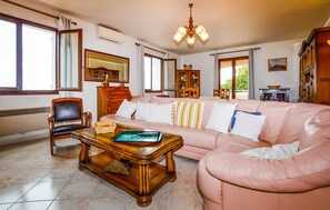 A living room with a pink sofa, a wooden coffee table, a chair, and a chandelier. - HAUT DE VILLA VUE MER AU CALME (CERVIONE)
