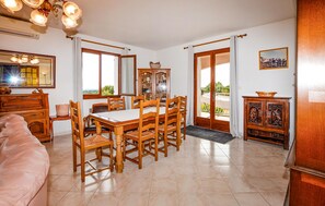 A dining room with a wooden table and chairs, a cabinet with glass doors, and a view through a door to an outdoor area. - HAUT DE VILLA VUE MER AU CALME (CERVIONE)