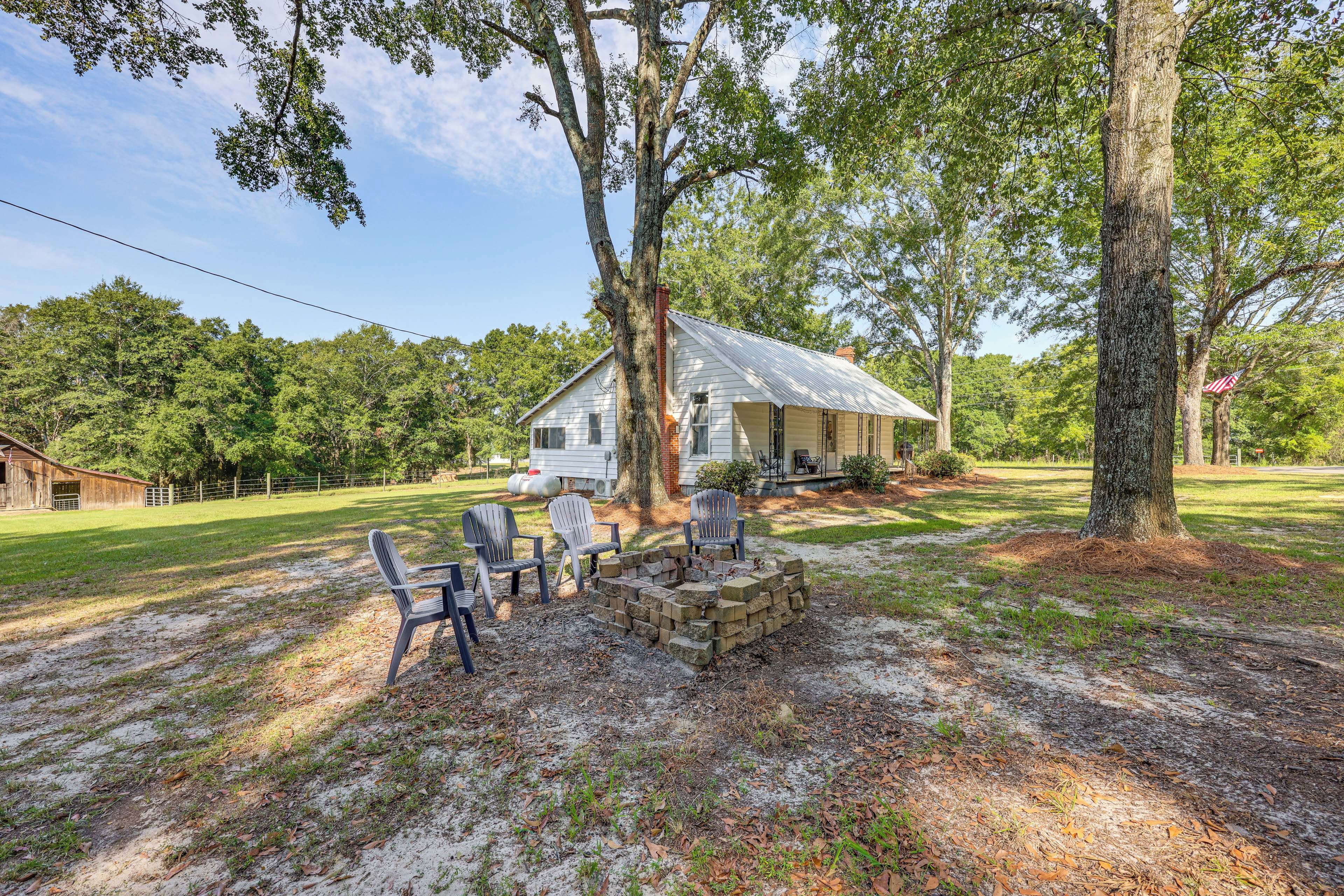 A rustic cabin with a porch, surrounded by trees and a grassy yard.