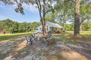 A rustic cabin with a porch, surrounded by trees and a grassy yard.