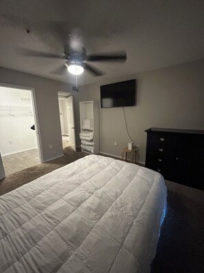 A bedroom with a bed, a ceiling fan, a TV, and a dresser. - Middle Of City Vibes (Atlanta)