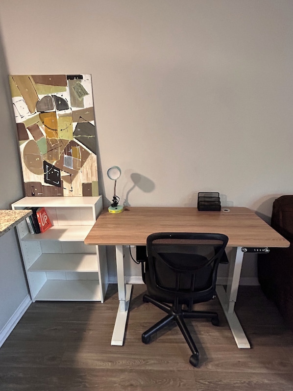 A small office space with a desk, chair, and a wall-mounted lamp.