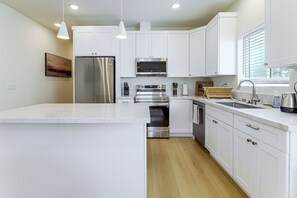 A modern kitchen with white cabinetry, stainless steel appliances, and pendant lighting. - LA Chic: Mid-City Home By Shopping & Hot Spots (Los Angeles)