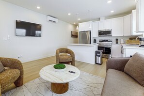 Ein modernes Wohnzimmer mit rundem Tisch, zwei Sofas und einem an der Wand befestigten Fernseher.