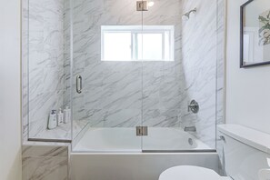 Ein modernes Badezimmer mit einer begehbaren Glasdusche, einer Badewanne und einer Toilette.