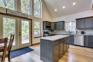 A modern kitchen with a central island, dark cabinetry, and large windows.
