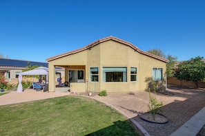 Einbungalow mit einer überdachten Terrasse, einem kleinen Garten und blauem Himmel.
