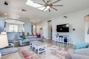 A spacious living room with a grey sofa, a coffee table, and a TV mounted on the wall. - Desert Oasis: Tucson Home w/ Private Swim Spa (Tucson)