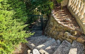 A stone staircase leading down to a garden area with a metal gate and lush greenery. - Vil. La Belle Vue avec piscice (Les Adrets de L' Ester)