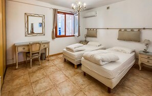 A bedroom with a desk, two beds, a chandelier, and an air conditioning unit. - Vil. La Belle Vue avec piscice (Les Adrets de L' Ester)