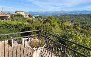A balcony with a view of a mountainous landscape, a building with a tiled roof, and a clear sky. - Vil. La Belle Vue avec piscice (Les Adrets de L' Ester)