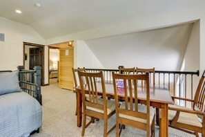 Ein Schlafzimmer mit einem Bett, einem Holzstuhl, einem Esstisch und einer Treppe, die in einen oberen Bereich führt.