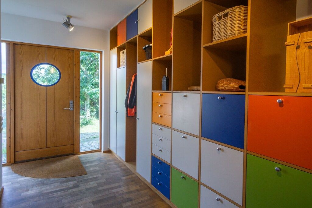 Un couloir avec une porte en bois, une grande armoire dotée de nombreux tiroirs et un panier en osier posé sur l’étagère supérieure.