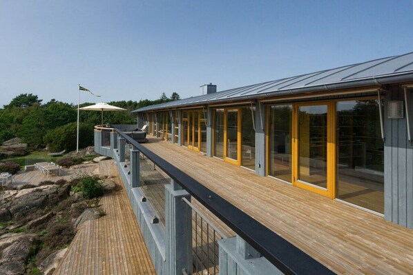 A wooden deck with glass railings overlooking a rocky landscape.