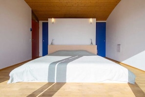 A bedroom with a bed, wooden floor, and a sloped ceiling.