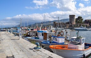 A harbor with boats docked, a stone building, and a clear sky.