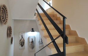 Eine Treppe mit schwarzen Geländern und beigen Stufen, die zu einer Zwischenebene mit Wandbildern führt.