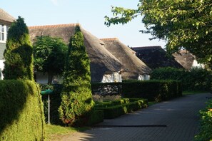 A residential street with houses, neatly trimmed hedges, and a clear sky. - Hoeve Duinzicht Burghduin 5 (Burgh-Haamstede)
