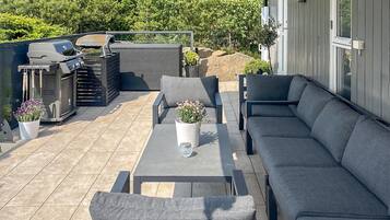 Eine Terrassenausstattung mit Grill, Sitzgelegenheit und Topfpflanzen.